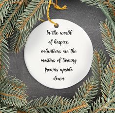 a white ornament hanging from a pine tree with the words in the world of hope written on it