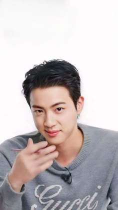 the young man is wearing a sweater and pointing at his finger