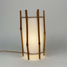 This unusual minimalist and natural designed table lamp was created by louis sognot and manufactured in france in the 1950s. The light is made of bamboo with an off-white cylindrical shade. The frame is constructed using vertical bamboo sticks tied together with wicker. The lamp's design evokes a rustic or zen aesthetic, likely suitable for a tranquil and earthy interior space. The lamp requires one e14 bulb. It has been rewired with new fabric cord. And comes with a continental european 2-pin p Earthy Interior, White Linen Table, Zen Aesthetic, Bamboo Lamp, Acrylic Light, Walnut Table, The 1950s, Lamp Design, White Linen