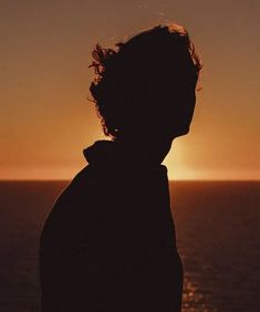 a person standing in front of the ocean at sunset