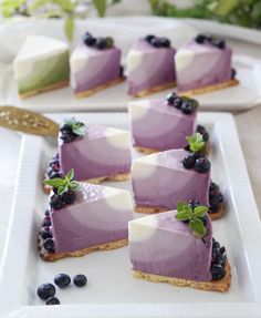 there are many desserts on the plate with blueberries and cream cheesecake in them