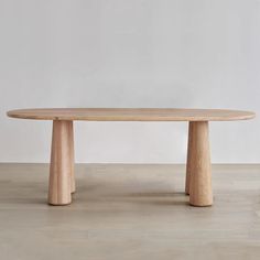 a wooden table sitting on top of a hard wood floor next to a white wall