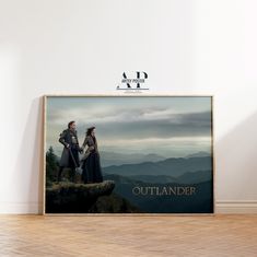 an advertisement for outlander with two people holding hands on top of a cliff in the mountains