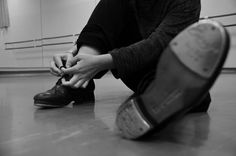 a man sitting on the floor tying his shoes