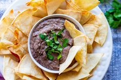 a white plate topped with tortilla chips and a bowl of black bean dip