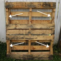 an old wooden crate with arrows pointing to the top and bottom, in front of a white fence