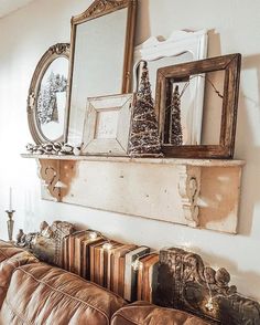 a living room filled with furniture next to a wall mounted mirror and framed pictures on top of a wooden shelf