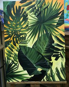 an easel with a painting of tropical leaves on it