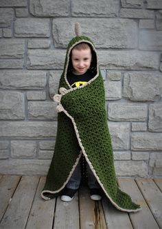 a young child wrapped in a green crocheted blanket