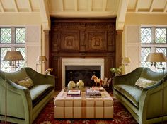 a living room with two green couches and a fire place in the middle of it