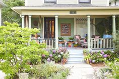 the front porch of a house with flowers and plants on the steps leading up to it