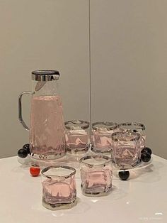 a pitcher and six glasses on a table