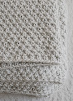 two white crocheted blankets folded on top of each other in the shape of squares