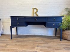 a blue desk with the letter r on it's top and two plants next to it