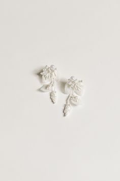 two pairs of white earrings with leaves and pearls on the end of each earring