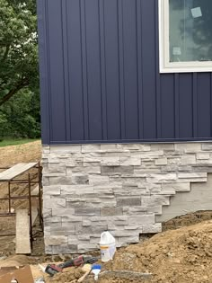 the side of a house that is under construction with some tools on the ground next to it