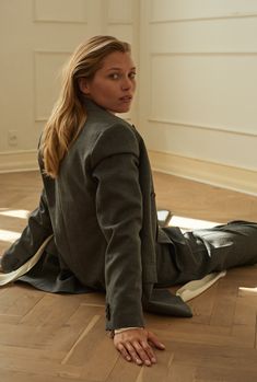 a woman sitting on the floor with her legs crossed and looking off to the side