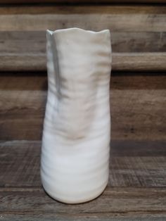 a white vase sitting on top of a wooden table