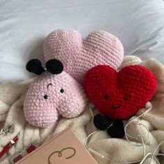 two crocheted stuffed animals laying on top of a bed next to a book