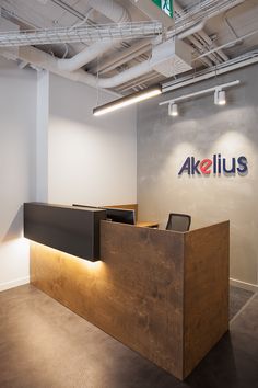 an office with a wooden reception desk in front of the akelius logo on the wall