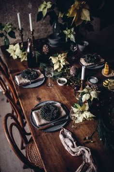 a wooden table topped with plates and bowls filled with food next to candles on top of it