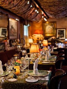 a dining room filled with lots of tables covered in white plates and place settings next to lamps