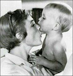 an old photo of a woman kissing a baby