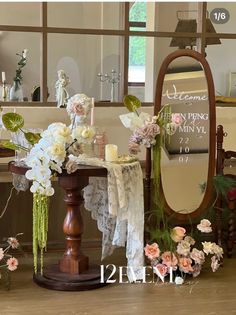 a table with flowers and candles on it in front of a mirror