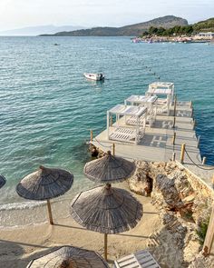 beach chairs and umbrellas are on the sand near the water