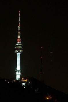 a very tall tower lit up at night with lights on it's spires