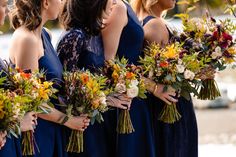 a group of women standing next to each other with bouquets in their hands and one woman wearing a blue dress