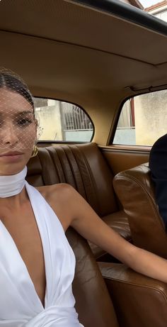 a woman sitting in the back seat of a car wearing a white halter top