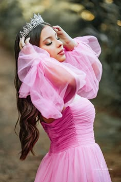 a woman in a pink dress with a tiara on her head is posing for the camera