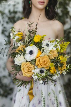 a woman holding a bouquet of yellow and white flowers