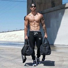 a man with no shirt holding two bags