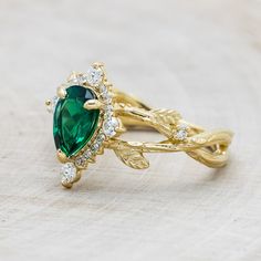 a close up of a ring with a green stone in the middle and white diamonds around it