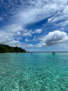 several boats floating in the ocean on a clear day with blue skies and white clouds