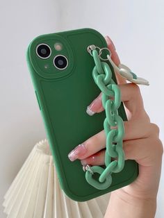 a woman holding up a green phone case with chains attached to it