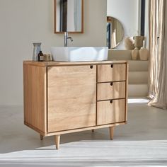 a bathroom sink sitting on top of a wooden cabinet next to a mirror and window