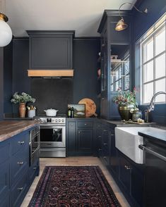 a kitchen with blue cabinets and an area rug in front of the stove top oven