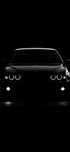 a black car in the dark with two lights on it's headlamps