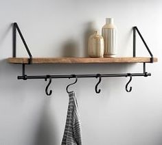 two black metal hooks are hanging on a wooden shelf next to a towel rack and vase