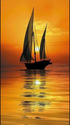 a sailboat floating in the ocean at sunset