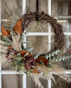 a wreath with dried flowers and leaves on a window sill