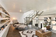 a living room filled with lots of furniture and bookshelves next to a stair case