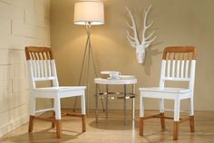 two chairs and a table in a room with deer heads on the wall behind them