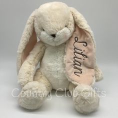 a white stuffed rabbit with a pink ribbon around its neck and name on the front