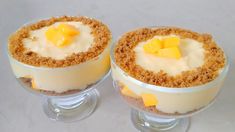 two desserts with cheese and crumbs in small glass dishes on a table