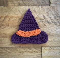 a purple crocheted hat with an orange ribbon on it sitting on a wooden surface