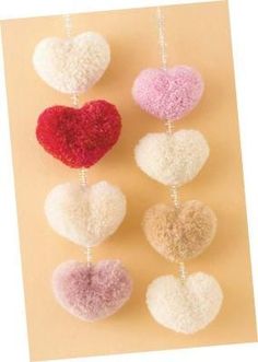 four heart ornaments hanging from strings on a postcard with the text diy heart shaped pom poms